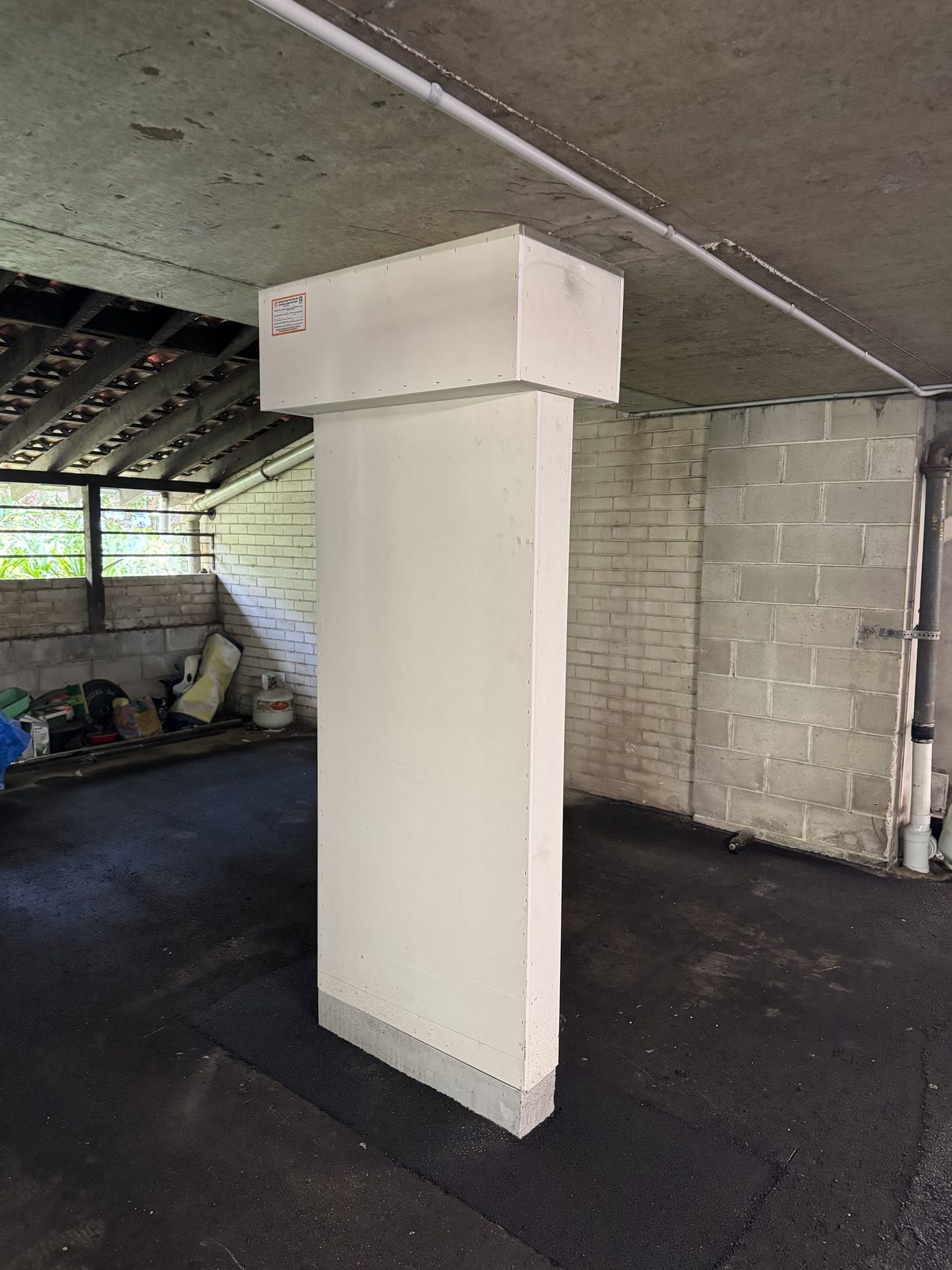 Structural steel column boxed out with Trafalgar Corex fire-rated board, finished white with FRL compliance label affixed, Sydney strata car park